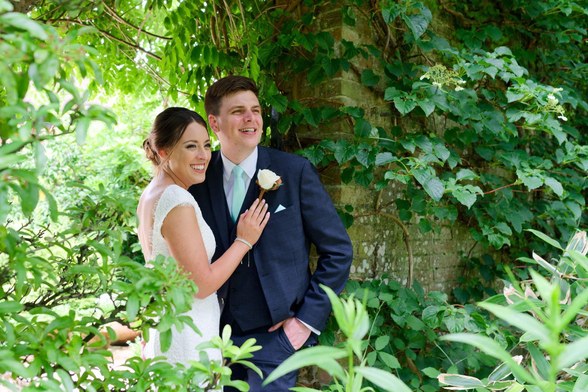 A bride and groom are posing for a picture in a garden.