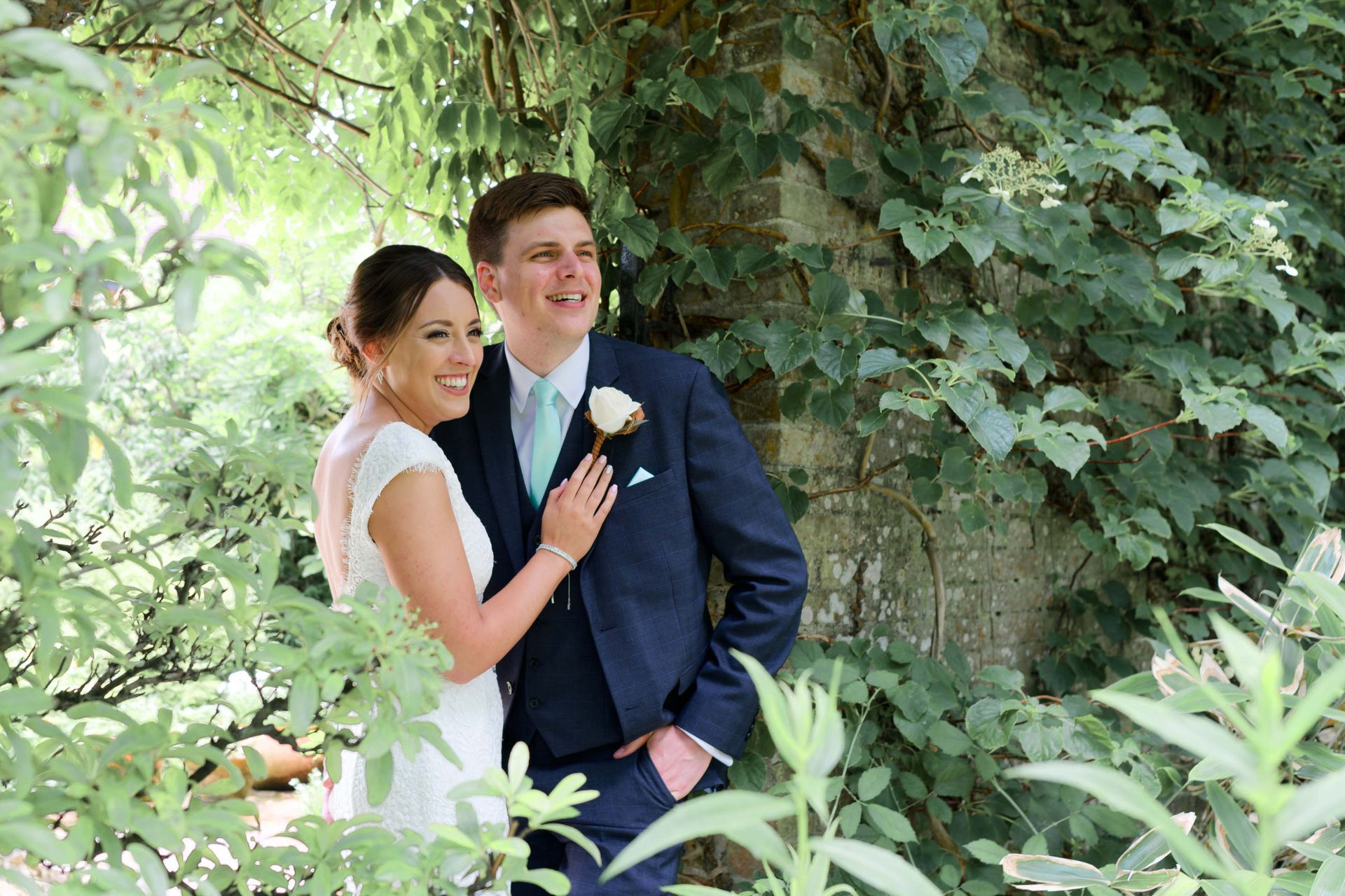 A bride and groom are posing for a picture in the woods.