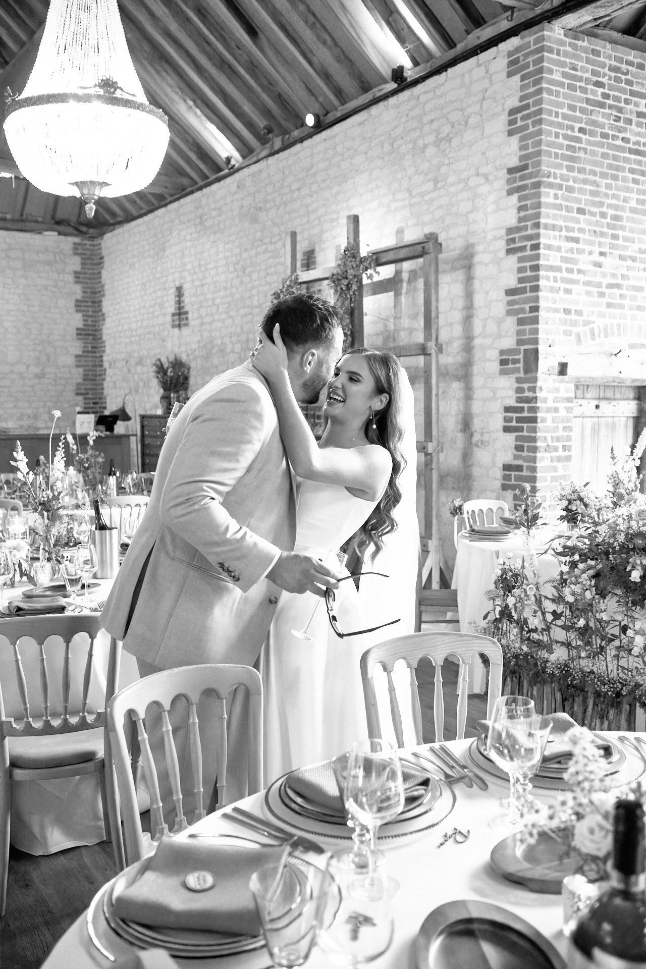 black and white wedding photography  of a bride and groom kissing at their wedding reception .