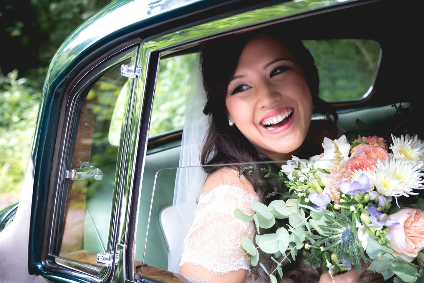 wedding photo of bride in car with wedding flowers