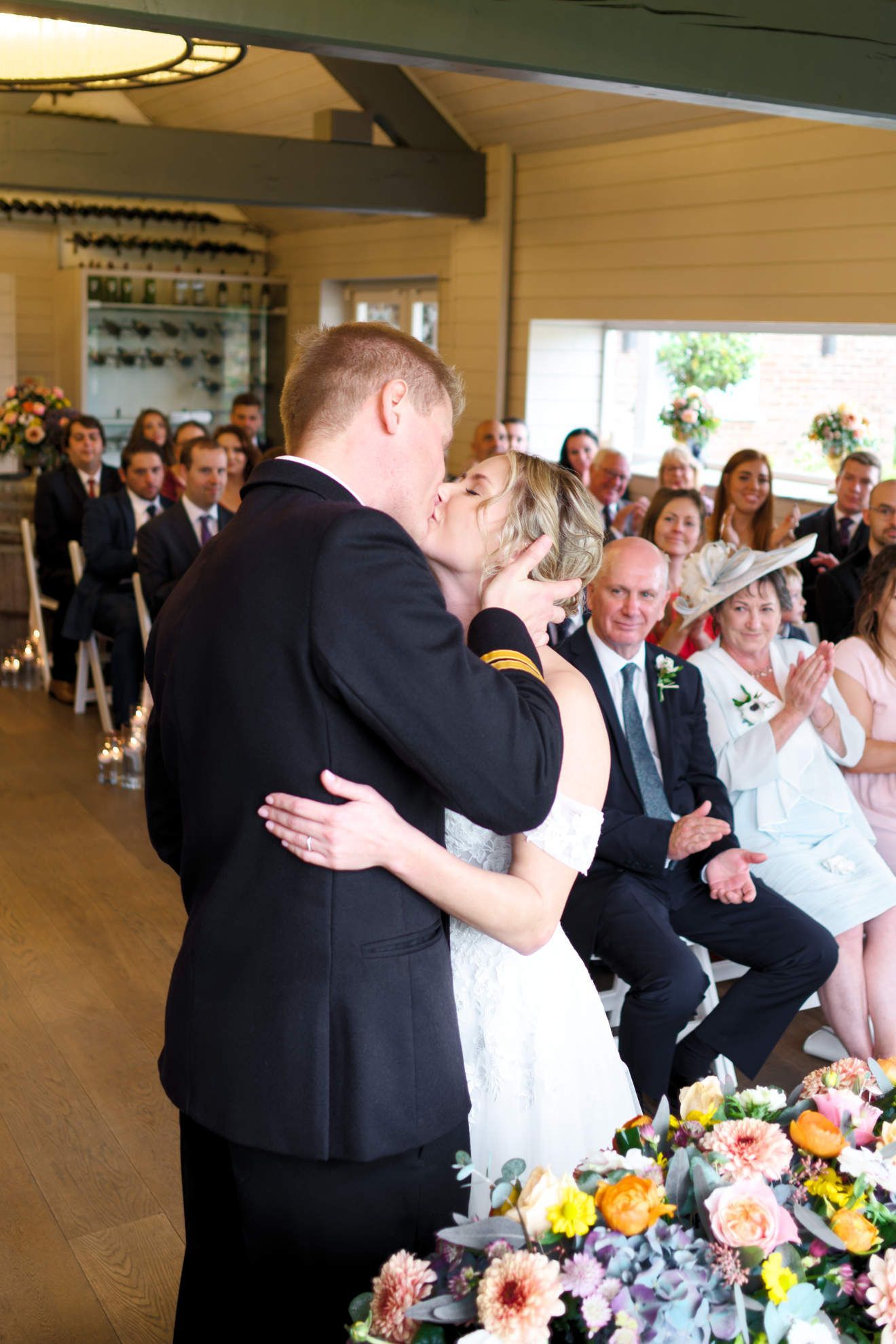 A bride and groom are kissing in front of a crowd at their wedding ceremony.