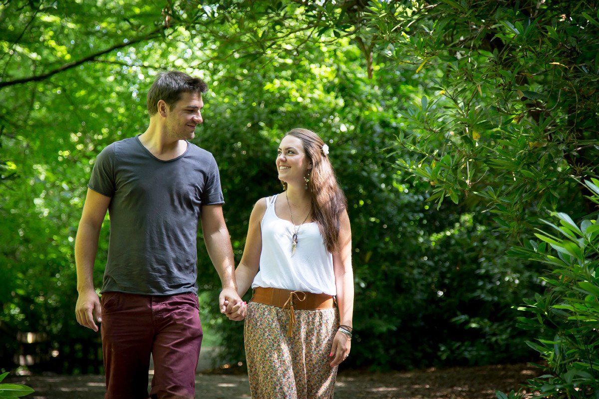 A man and a woman are walking in a park holding hands.