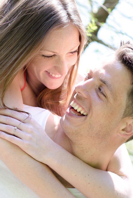 A man and a woman are hugging each other and smiling.