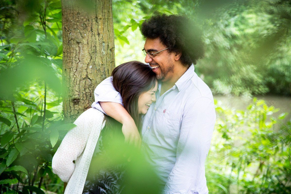A man and a woman are hugging each other in the woods.