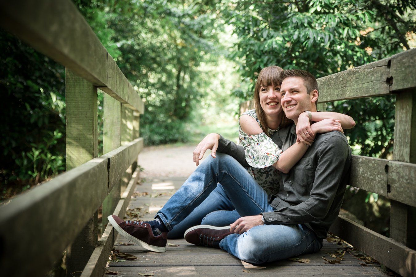 A man and a woman are sitting on a wooden bridge.