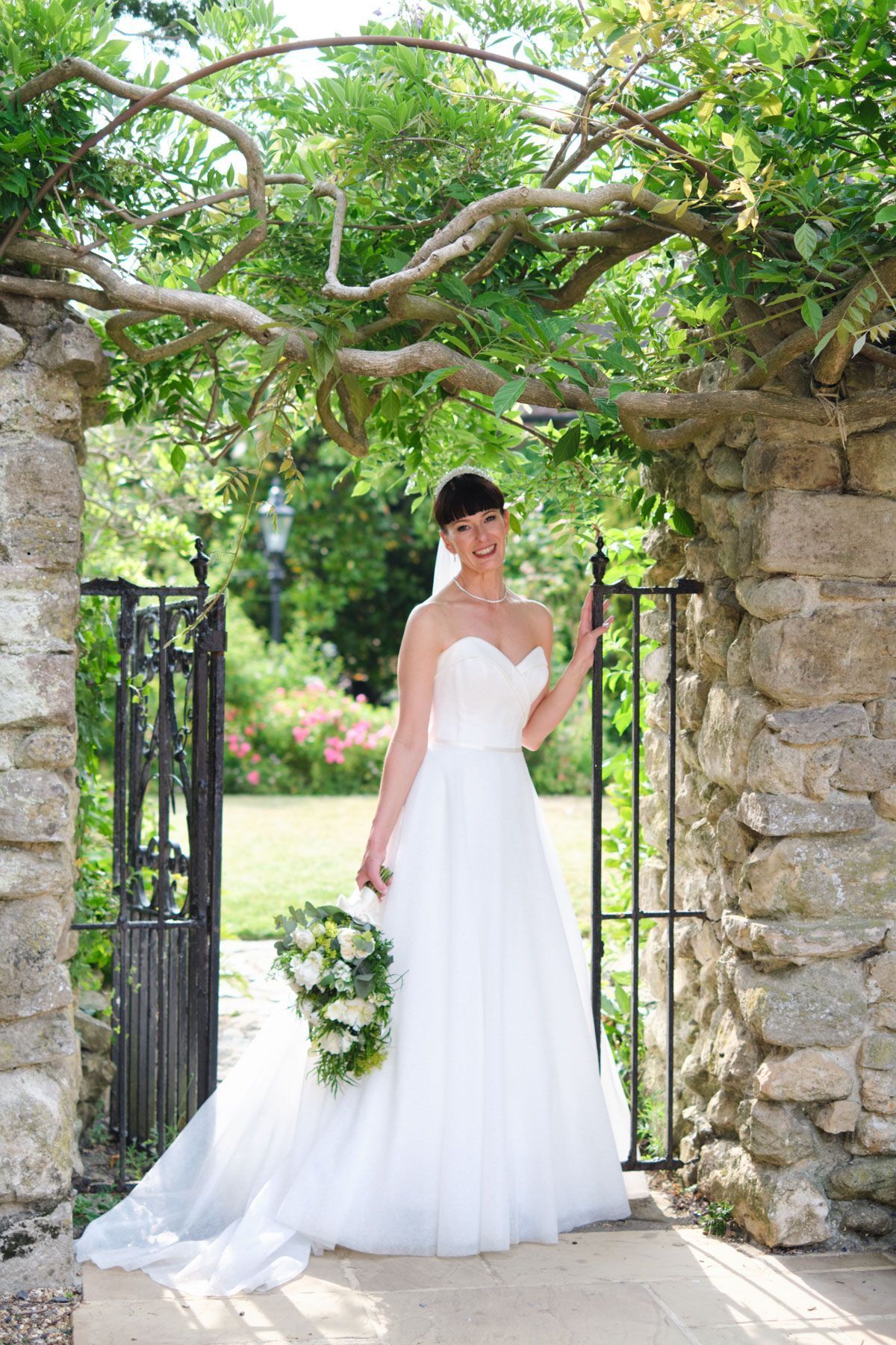 The bride is wearing a white wedding dress and holding a bouquet of flowers.