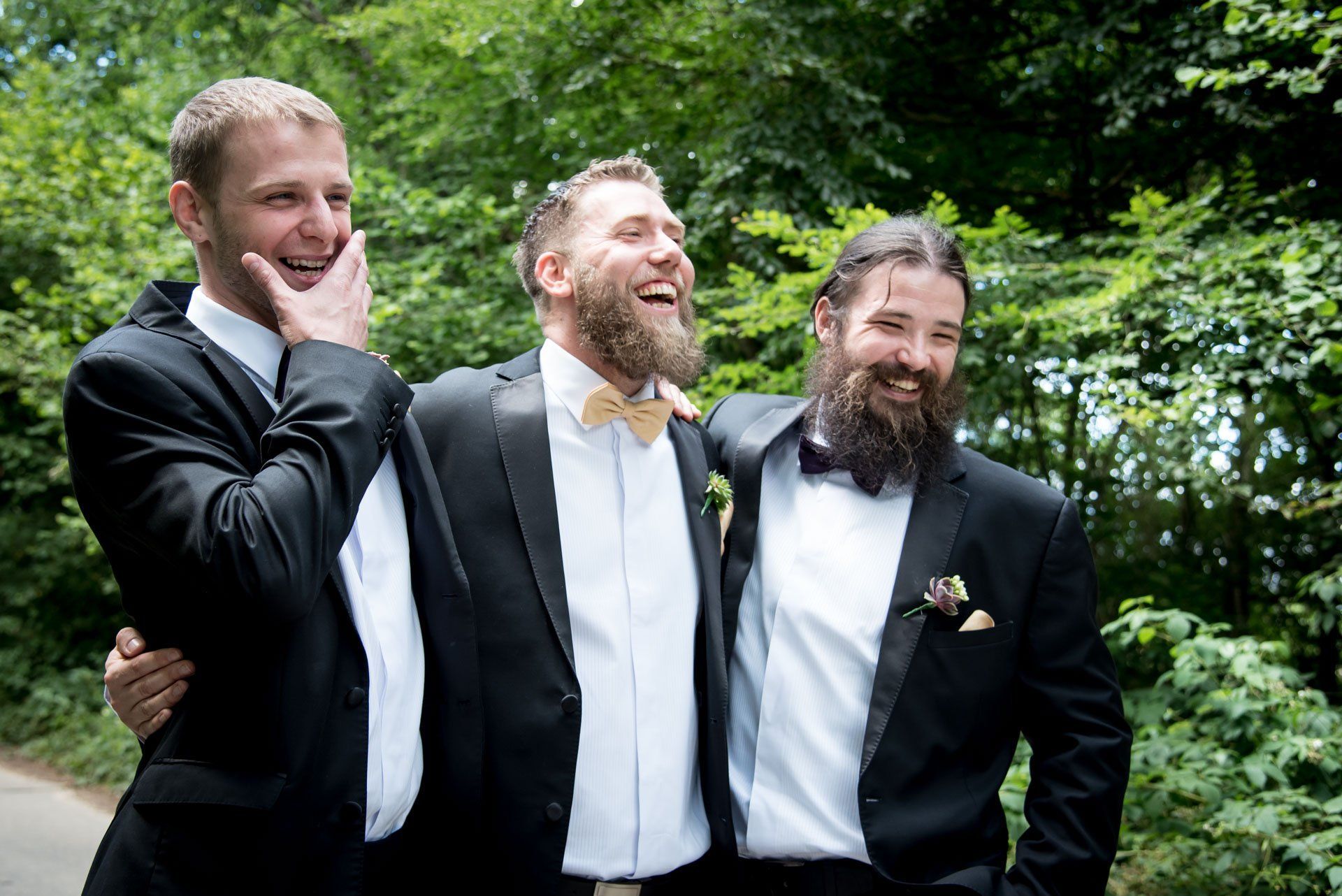 Three men in suits and bow ties are posing for a picture.
