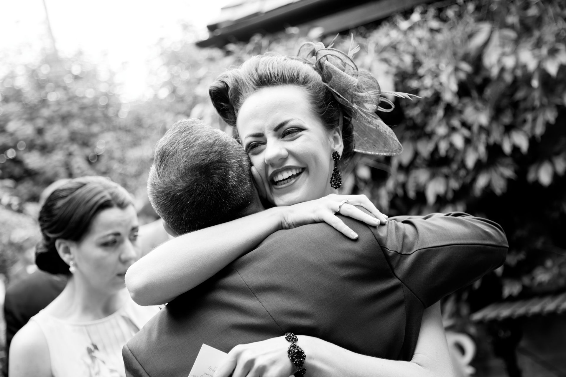 A woman in a hat is hugging a man in a suit.