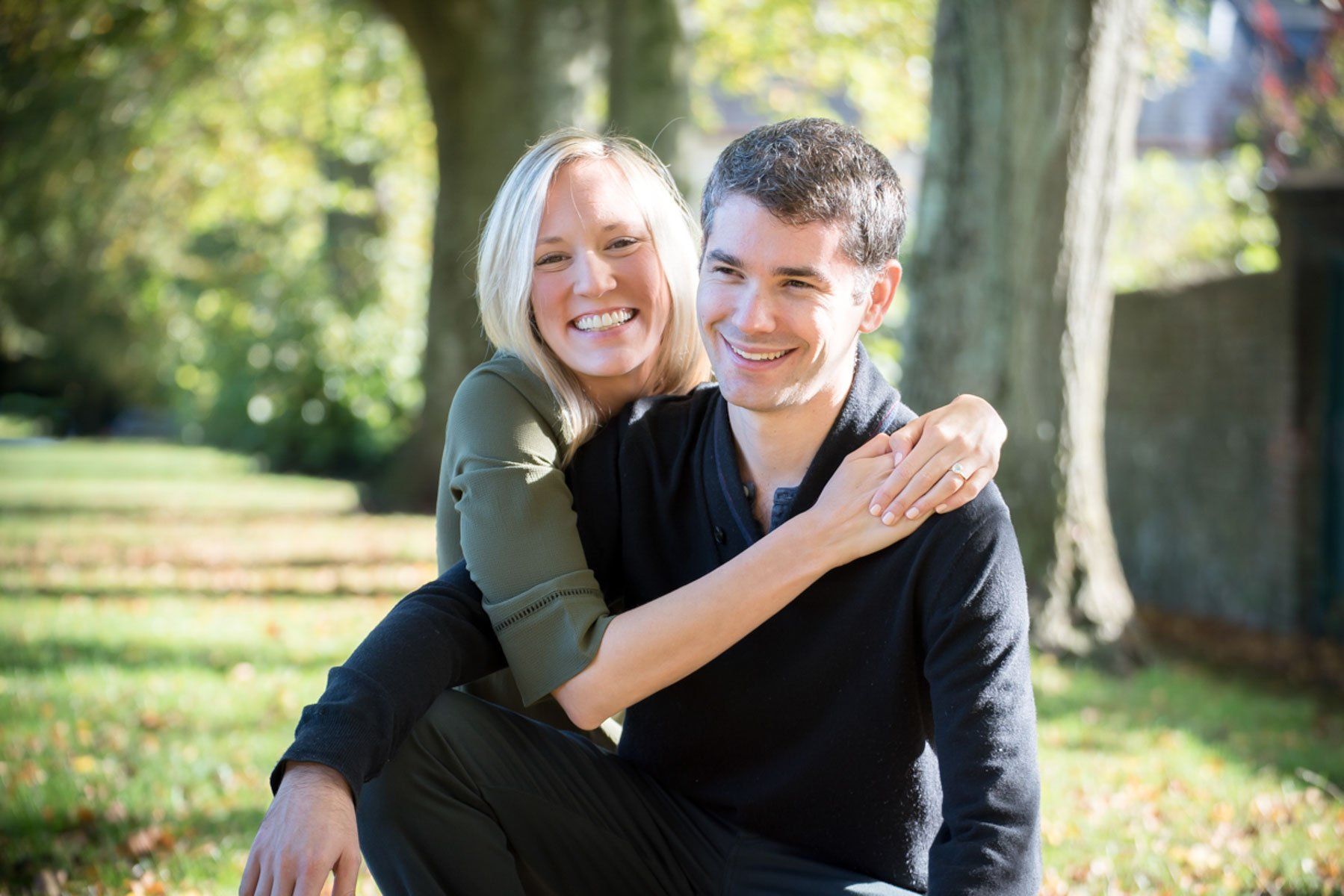 A man and a woman are sitting on the grass in a park.