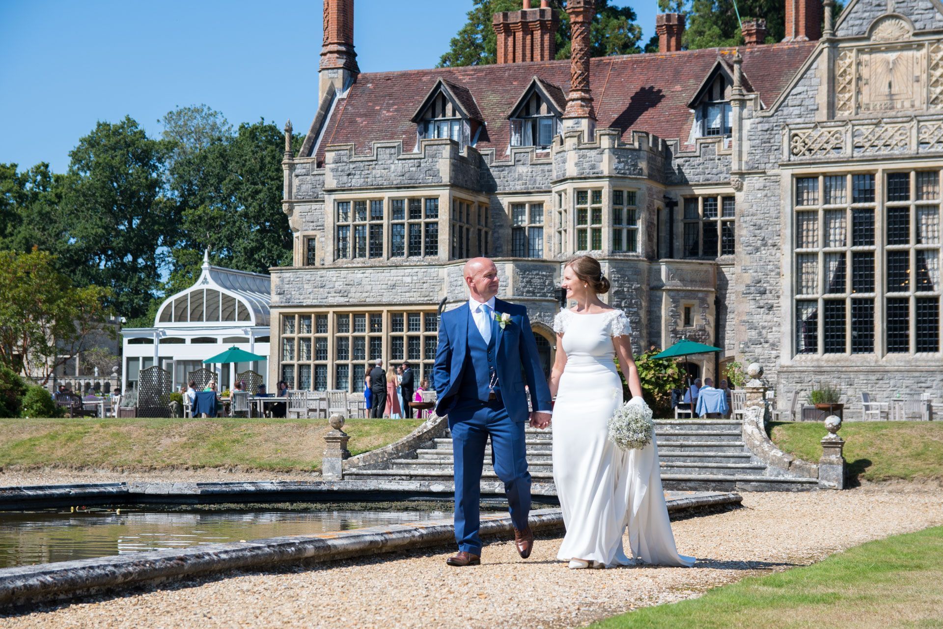 A bride and groom are walking in front of a large building.