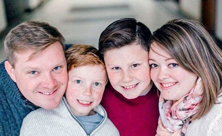 A family is posing for a picture together and smiling for the camera.