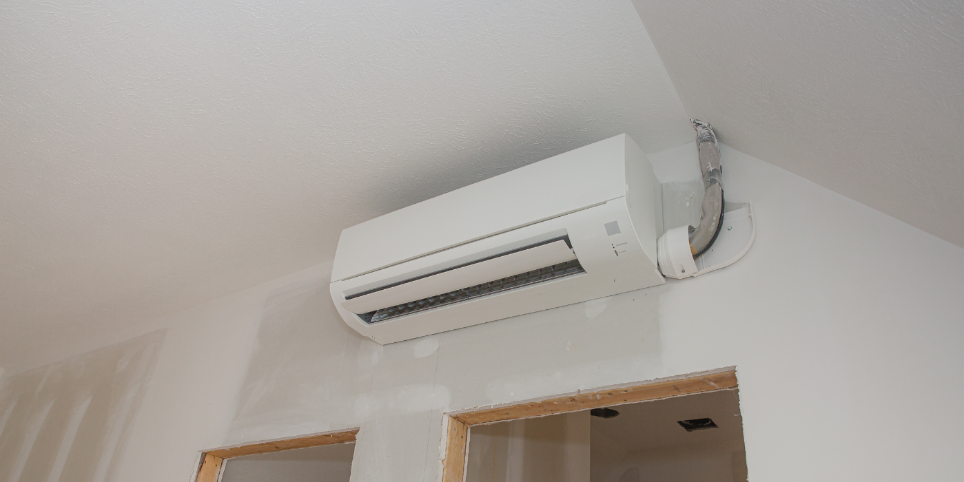 A white air conditioner is hanging from the ceiling in a room.