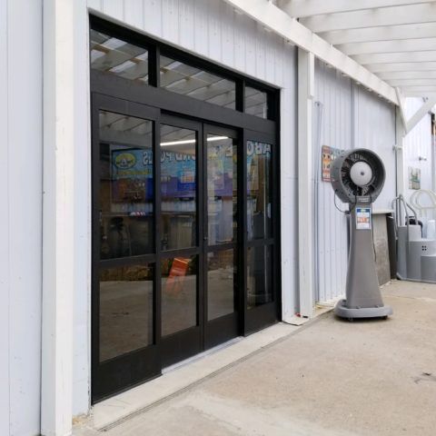 A building with a sliding glass door and a fan in front of it.