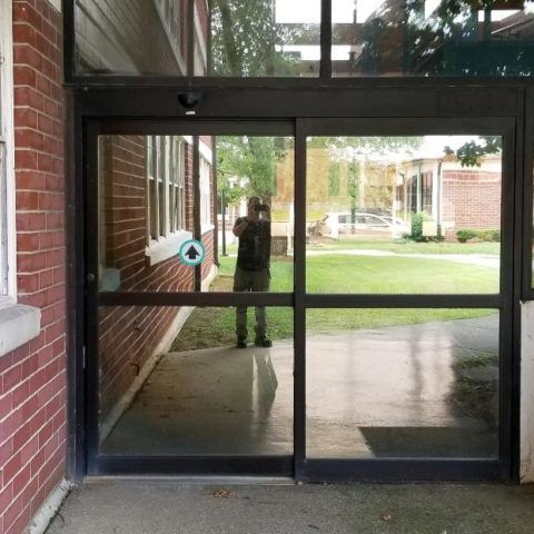 A man is standing in front of a sliding glass door