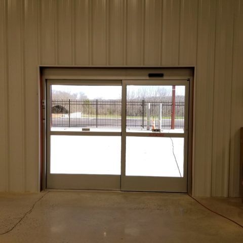 Automatic Doors Installation and Repair - A sliding glass door in a building with a fence in the background.