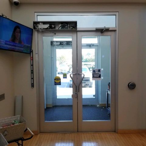 A waiting room with two glass doors and a tv on the wall