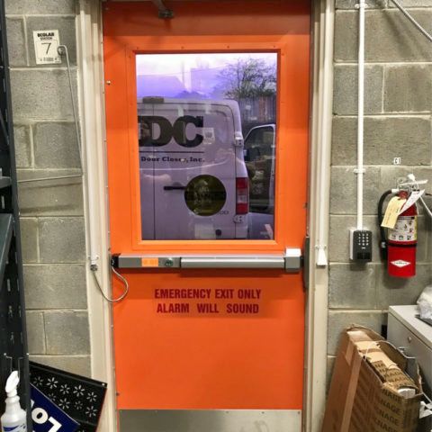 An orange door that says emergency exit only alarm will sound