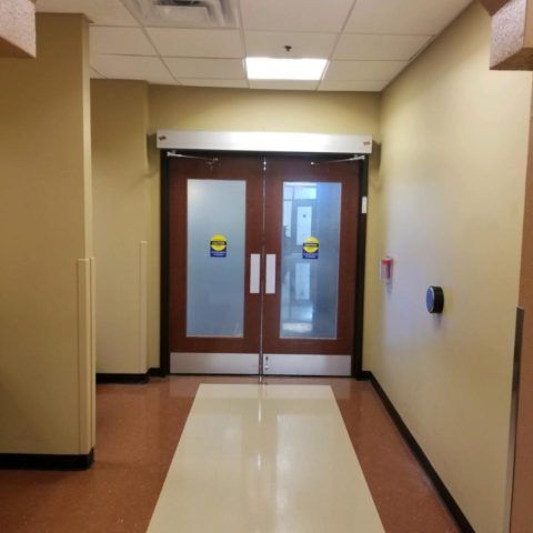 A hallway with a door that has a sticker on it that says ' emergency exit '