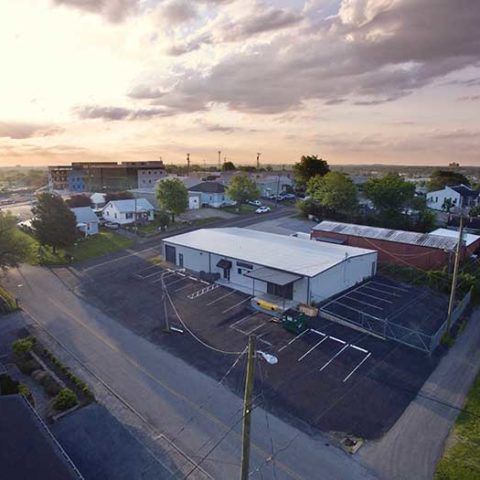 An aerial view of a building and a parking lot in a small town.