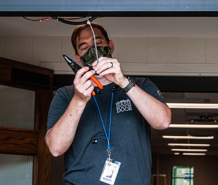 A man wearing a mask is holding a pair of pliers