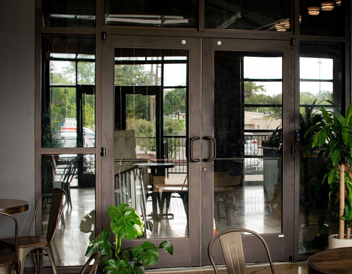 A restaurant with a lot of glass doors and tables and chairs.