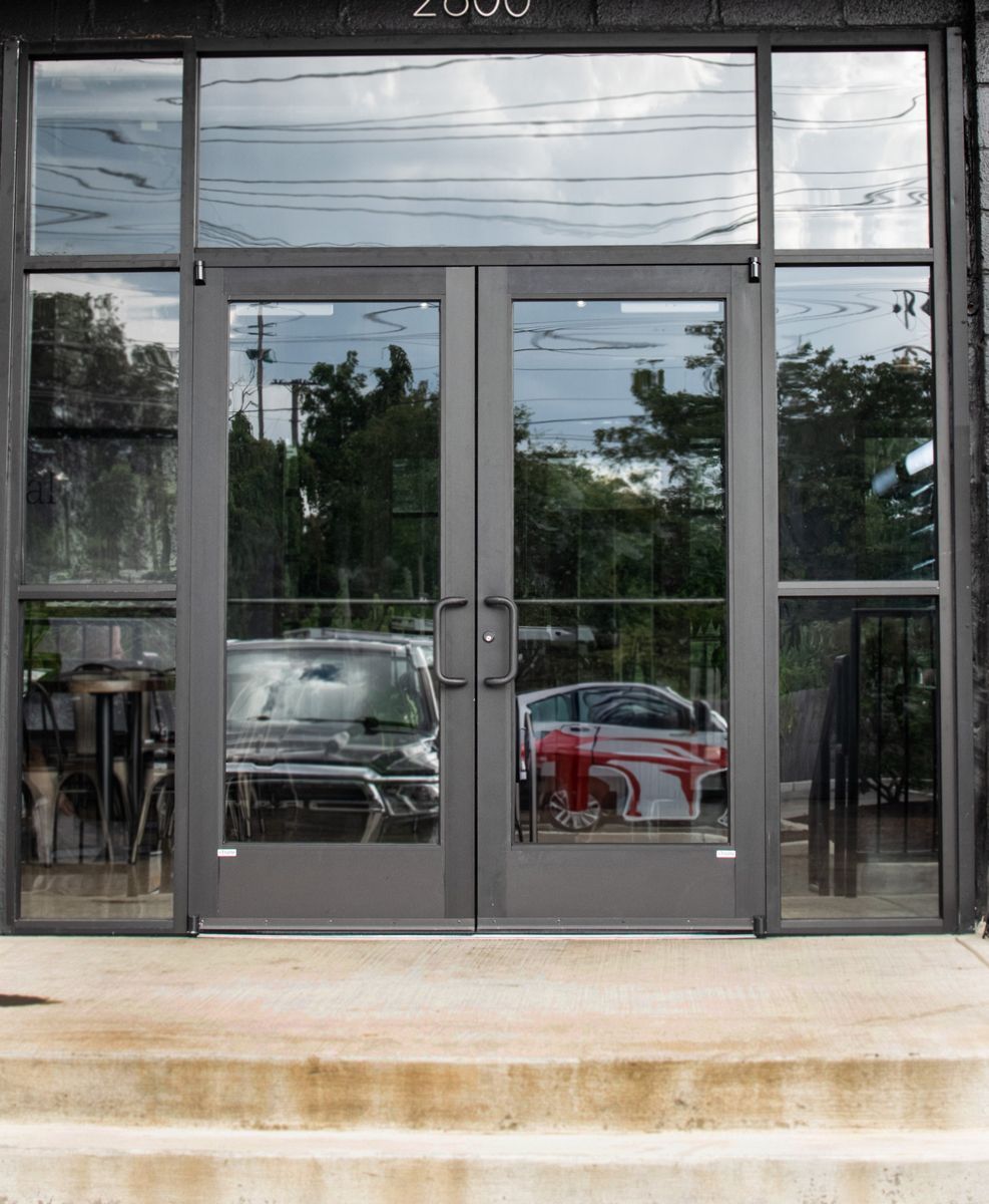 A car is reflected in the glass doors of a building