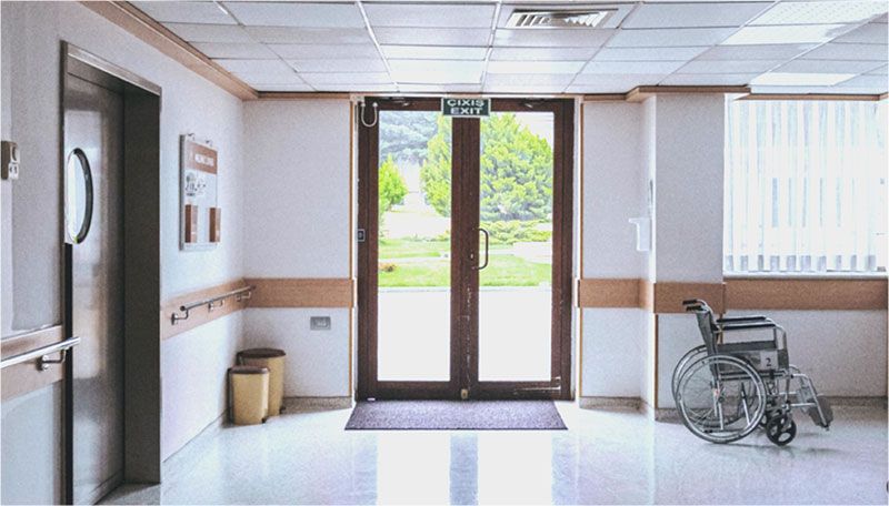 There is a wheelchair in the hallway of a hospital.