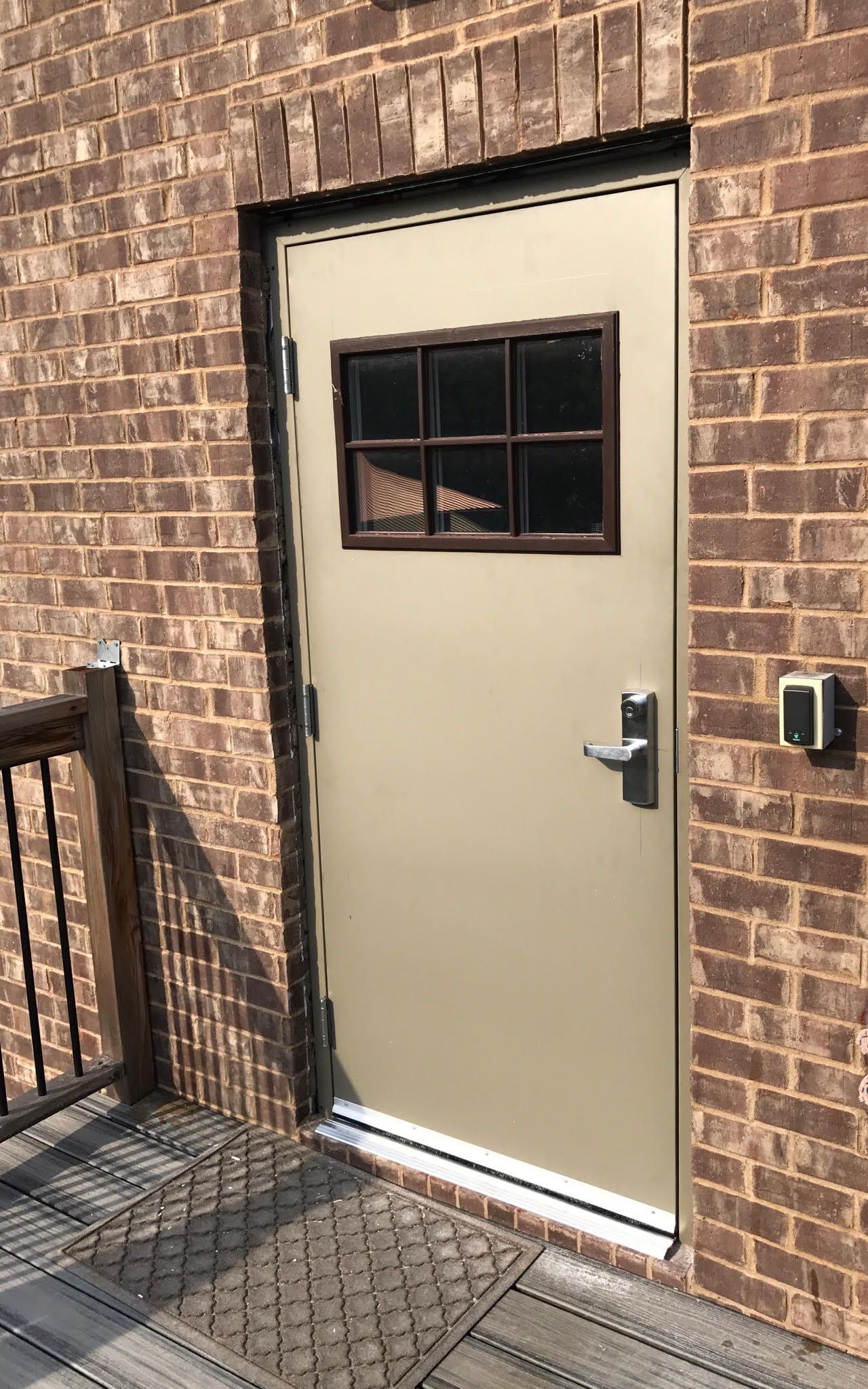A door with a window on the side of a brick building.