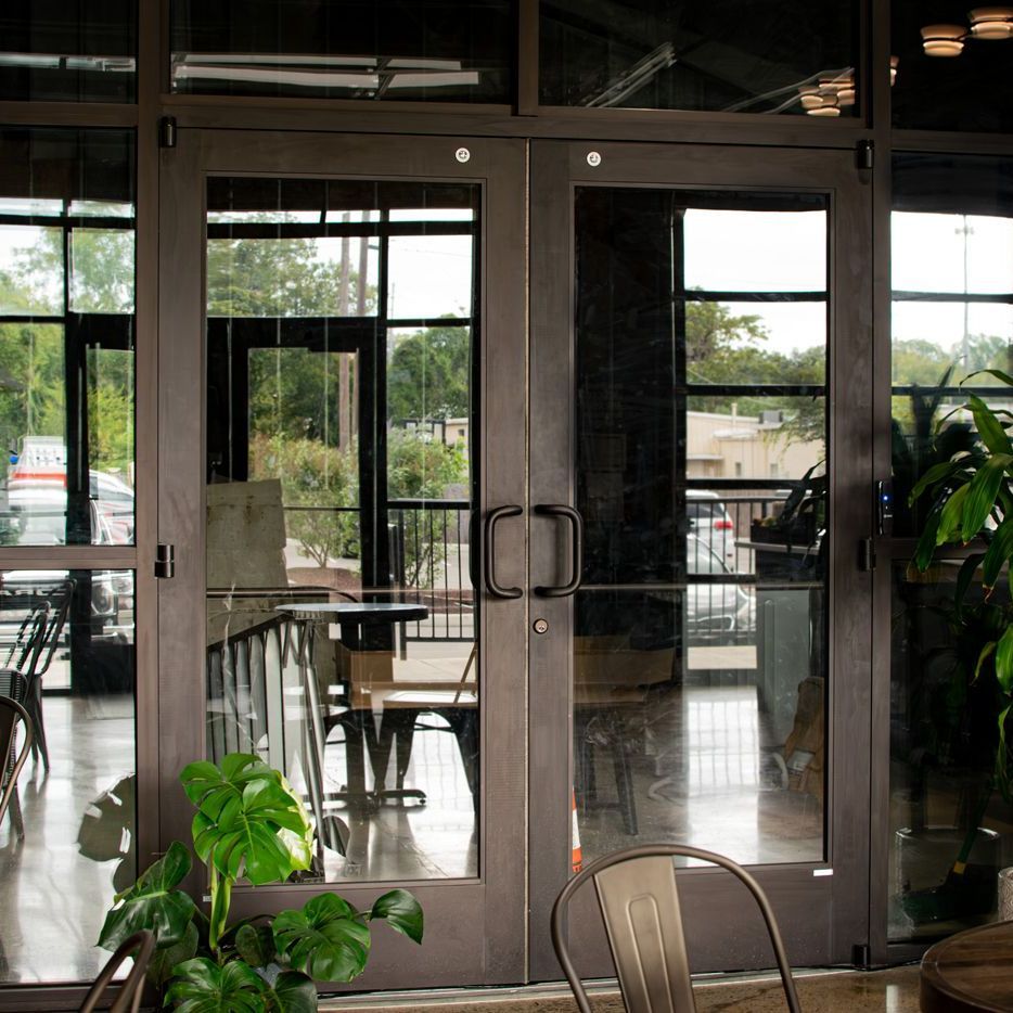 A restaurant with a plant in front of the doors