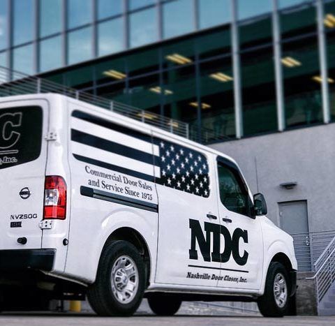 A white ndc van is parked in front of a building