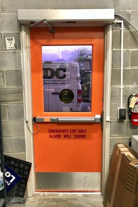 An orange door with a window and a sign that says emergency exit only