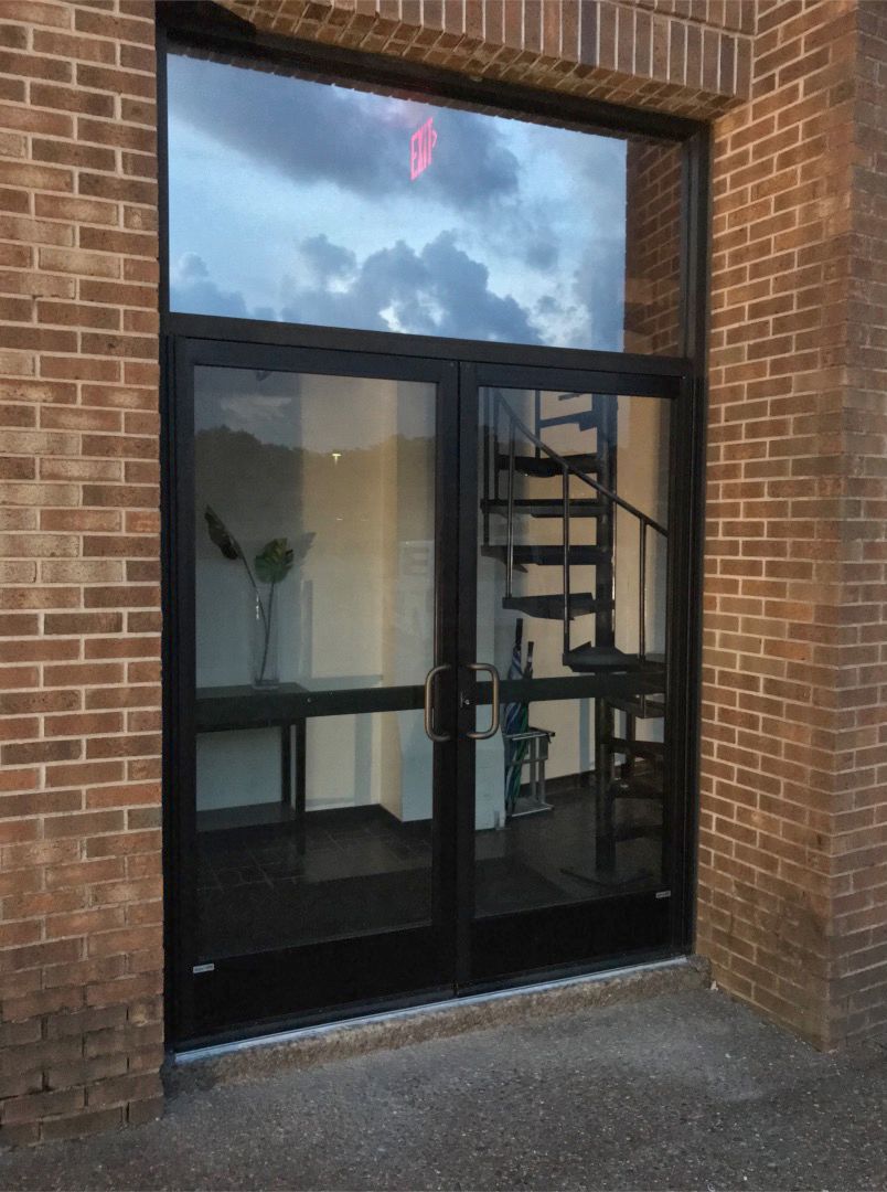Storefronts & Glass Doors Installation and Repair - A brick building with a glass door and a spiral staircase