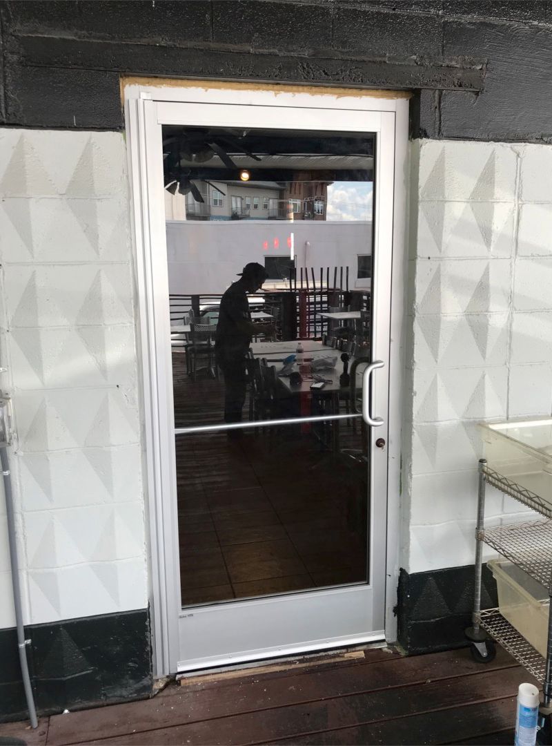 Storefronts & Glass Doors Installation and Repair - A man is standing in a room behind a glass door.