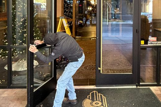 Nashville Commercial Door Installation and Repair - A man in a hoodie is breaking into a building.