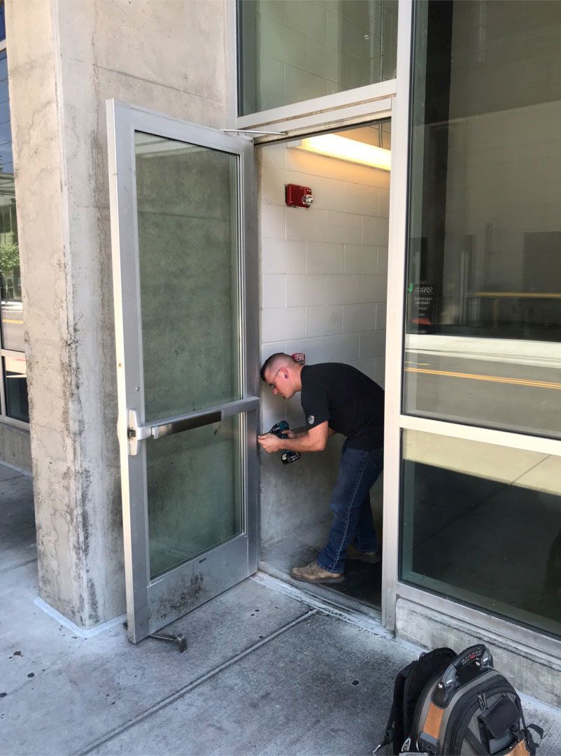 A man is working on a door with a screwdriver.