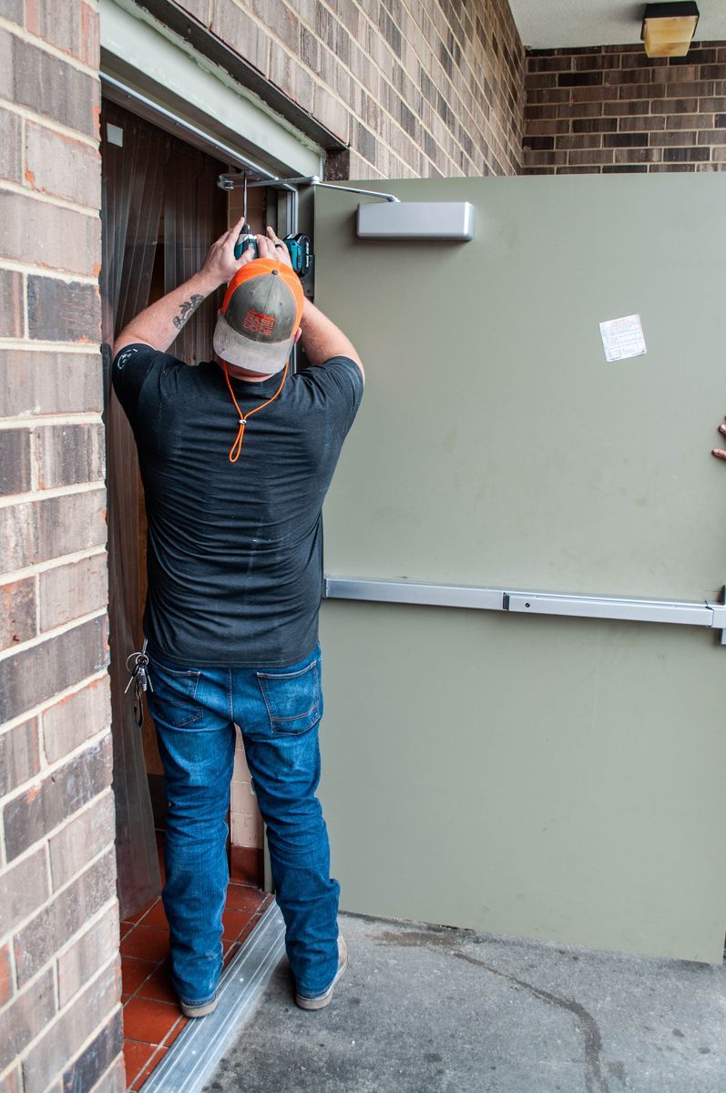 A man is standing in a doorway holding a drill.