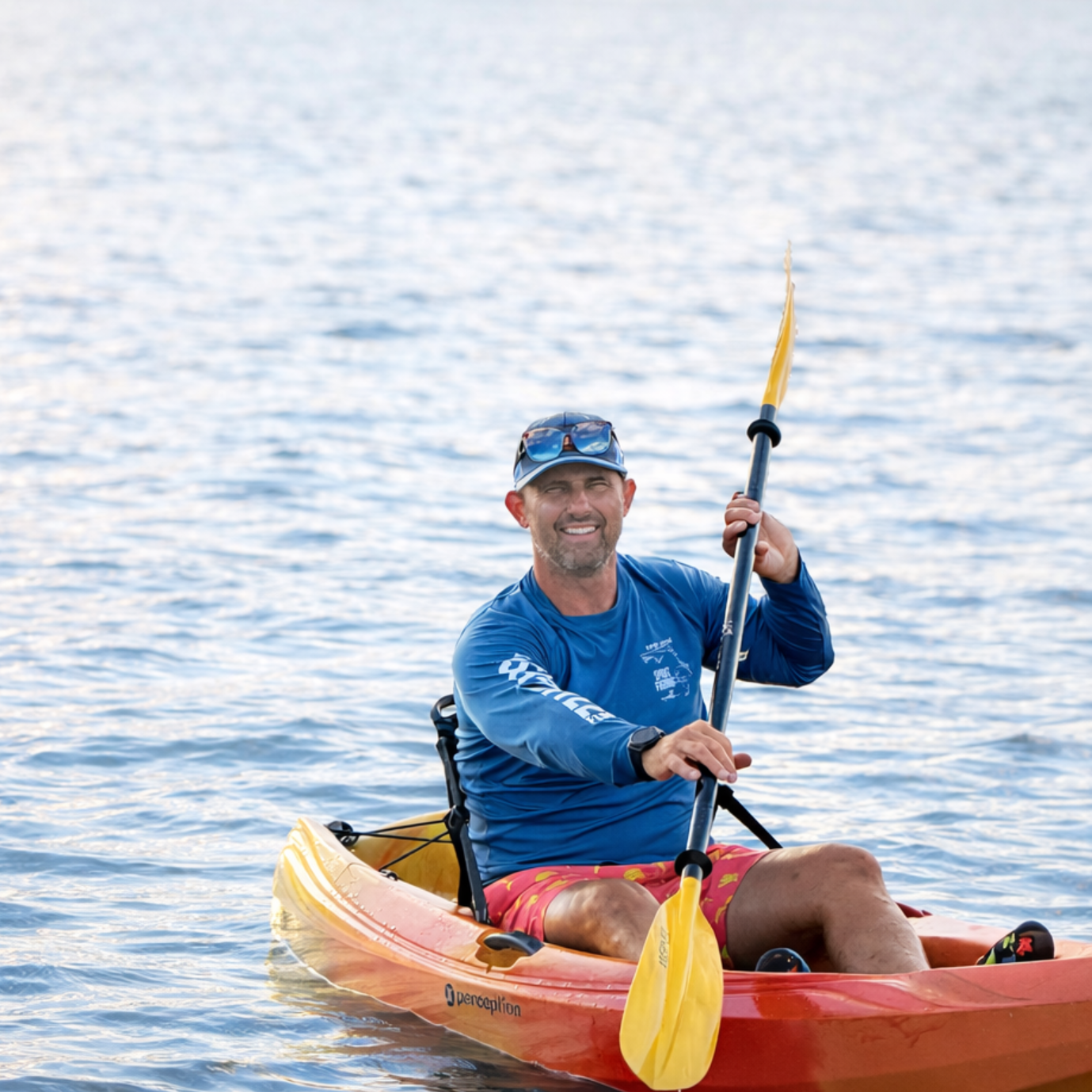 Man holding a kayak, standing near a Las Vegas Canoe Kayak Club banner. Outdoor setting.