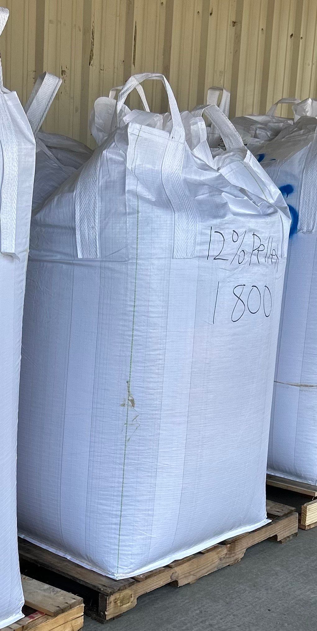 A pallet of orange buckets wrapped in plastic is sitting on the ground.