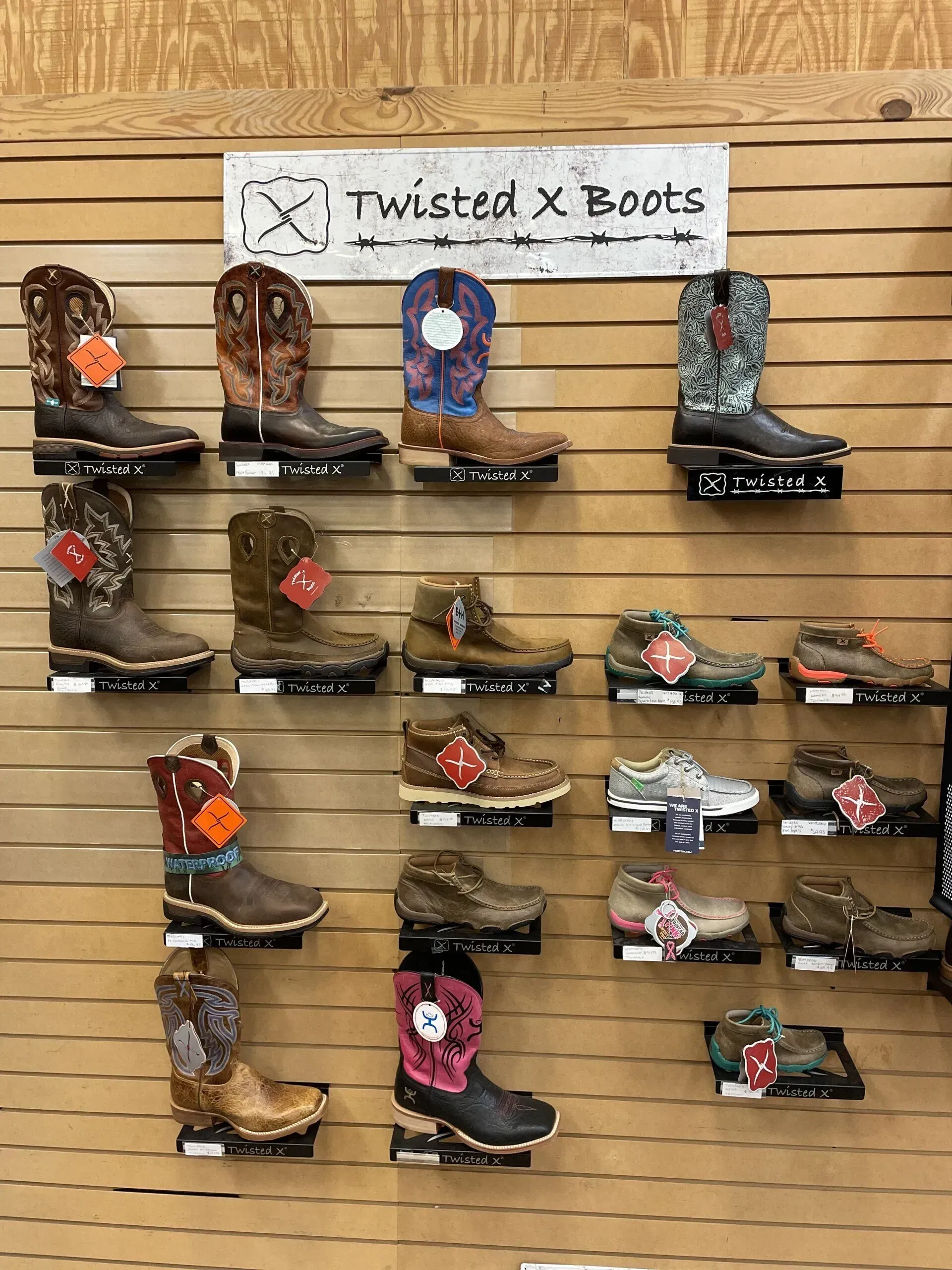 A display of cowboy boots on a wall in a store.
