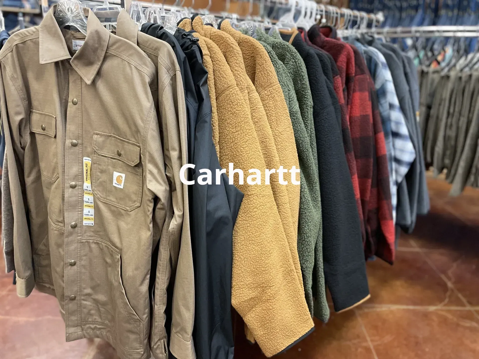 A row of carhartt jackets hanging on a rack in a store.