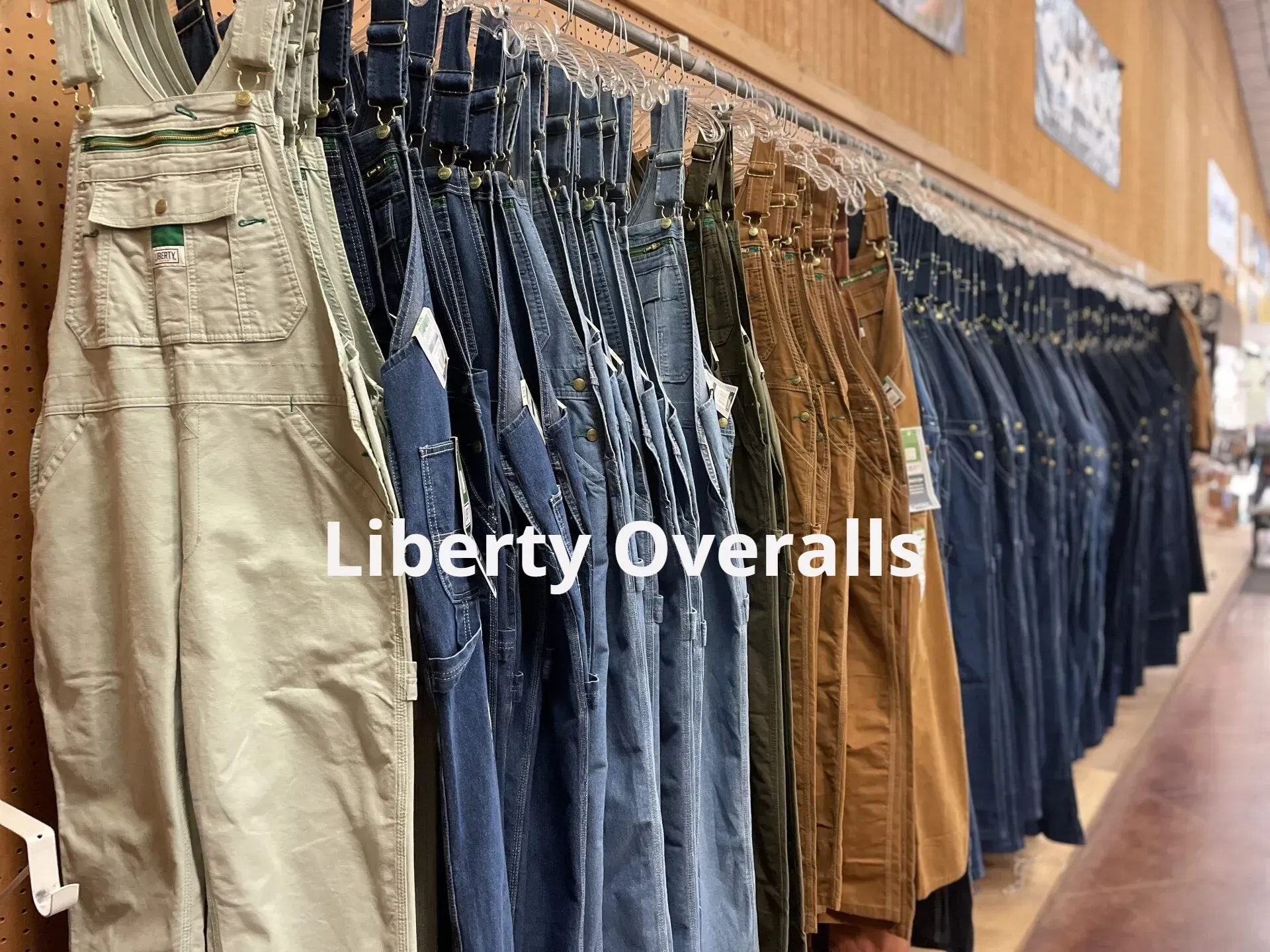 A row of overalls hanging on a rack in a store.