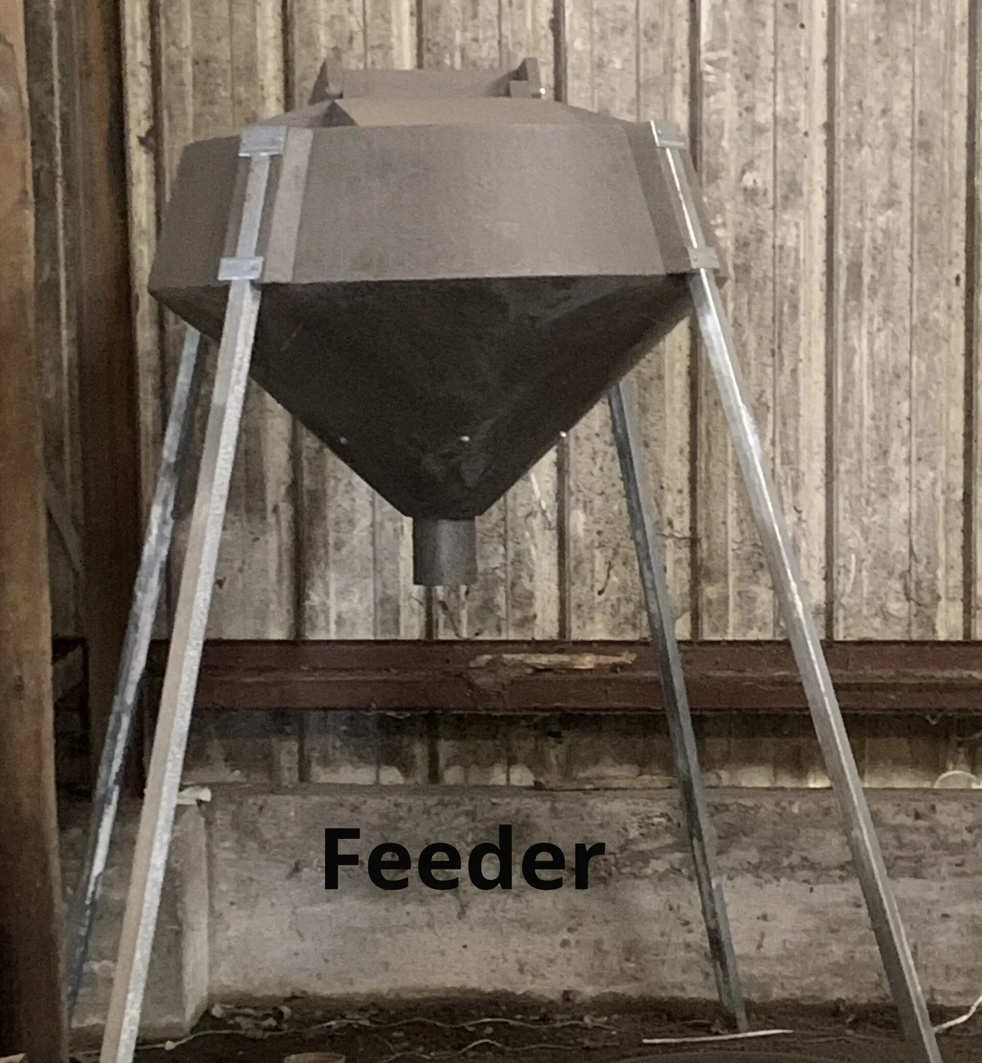 A feeder is sitting in front of a wooden wall.