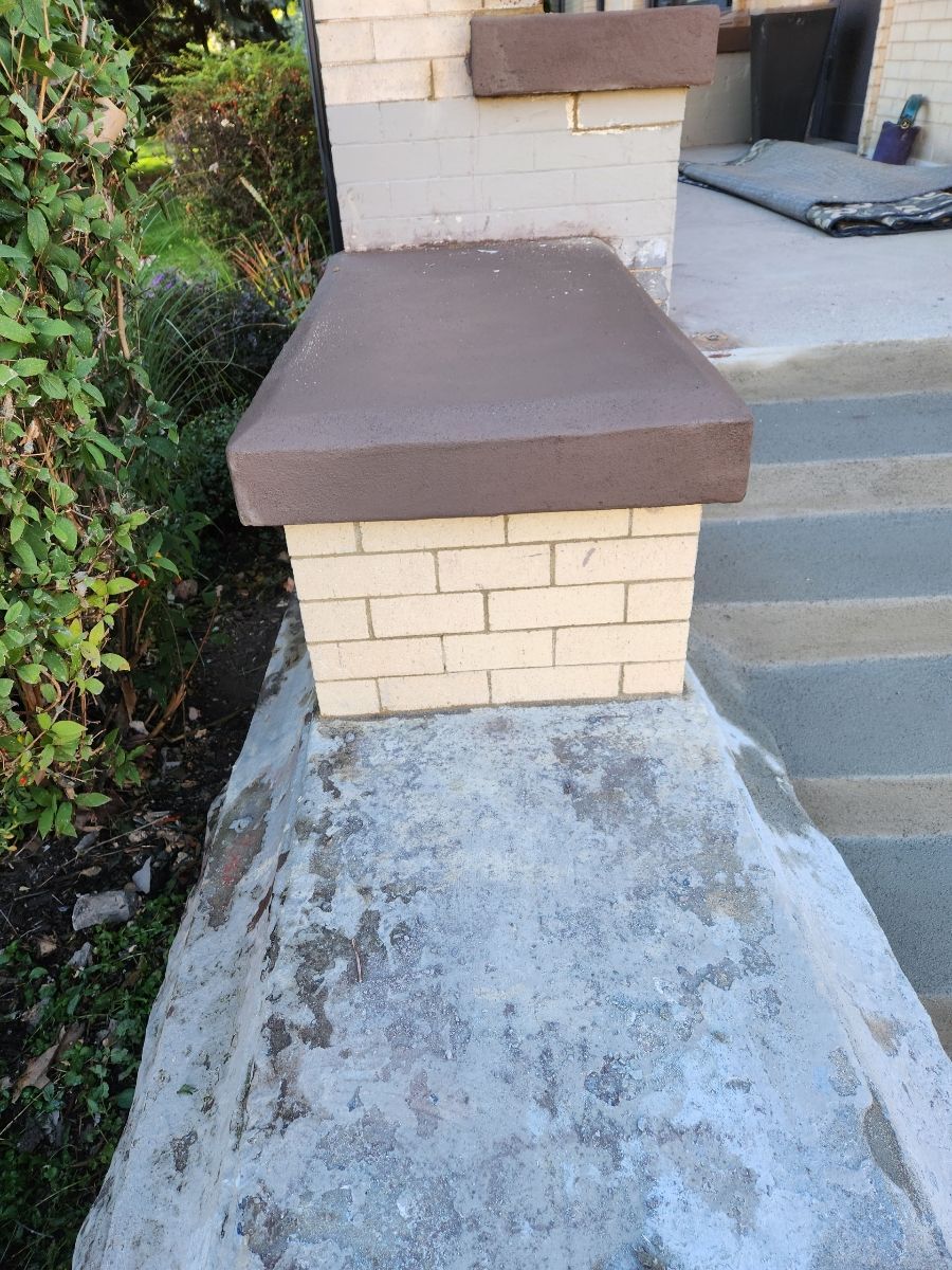 Brick pillar with brown cap on porch steps.