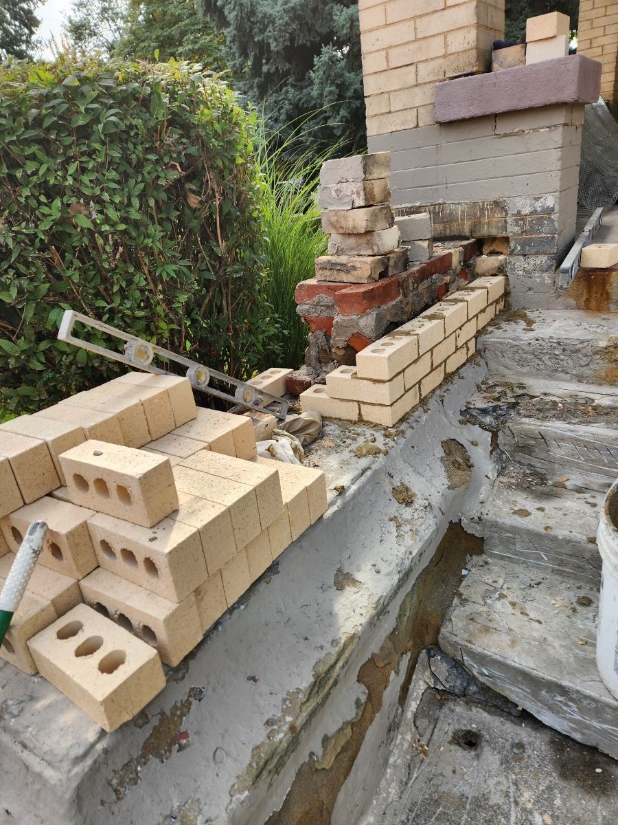 Bricklaying work in progress outdoors, with stacks of bricks, a level, and a partly constructed structure.
