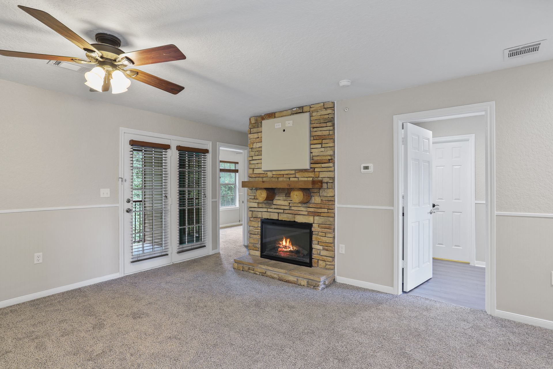 Photo of a living room witha a fireplace and a ceiling fan