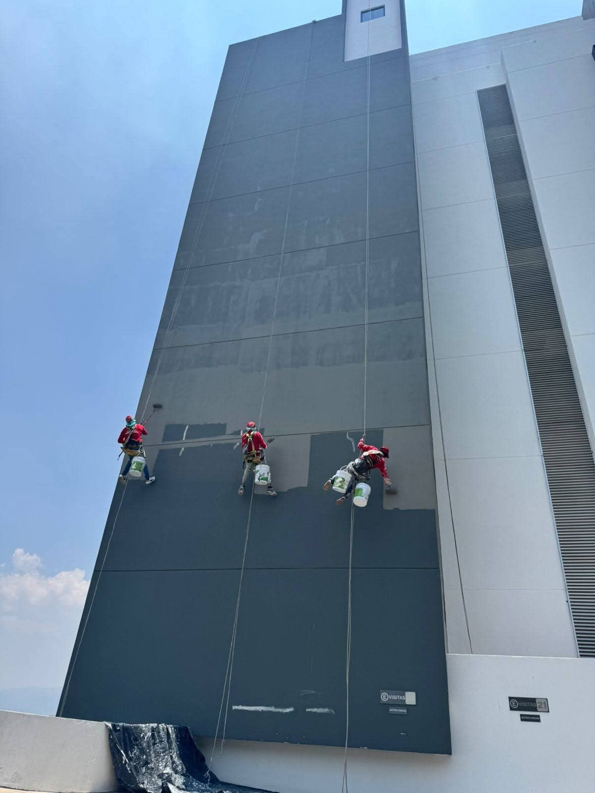 Trabajadores pintando y ajardinando la fachada de una hilera de casas nuevas en los suburbios.