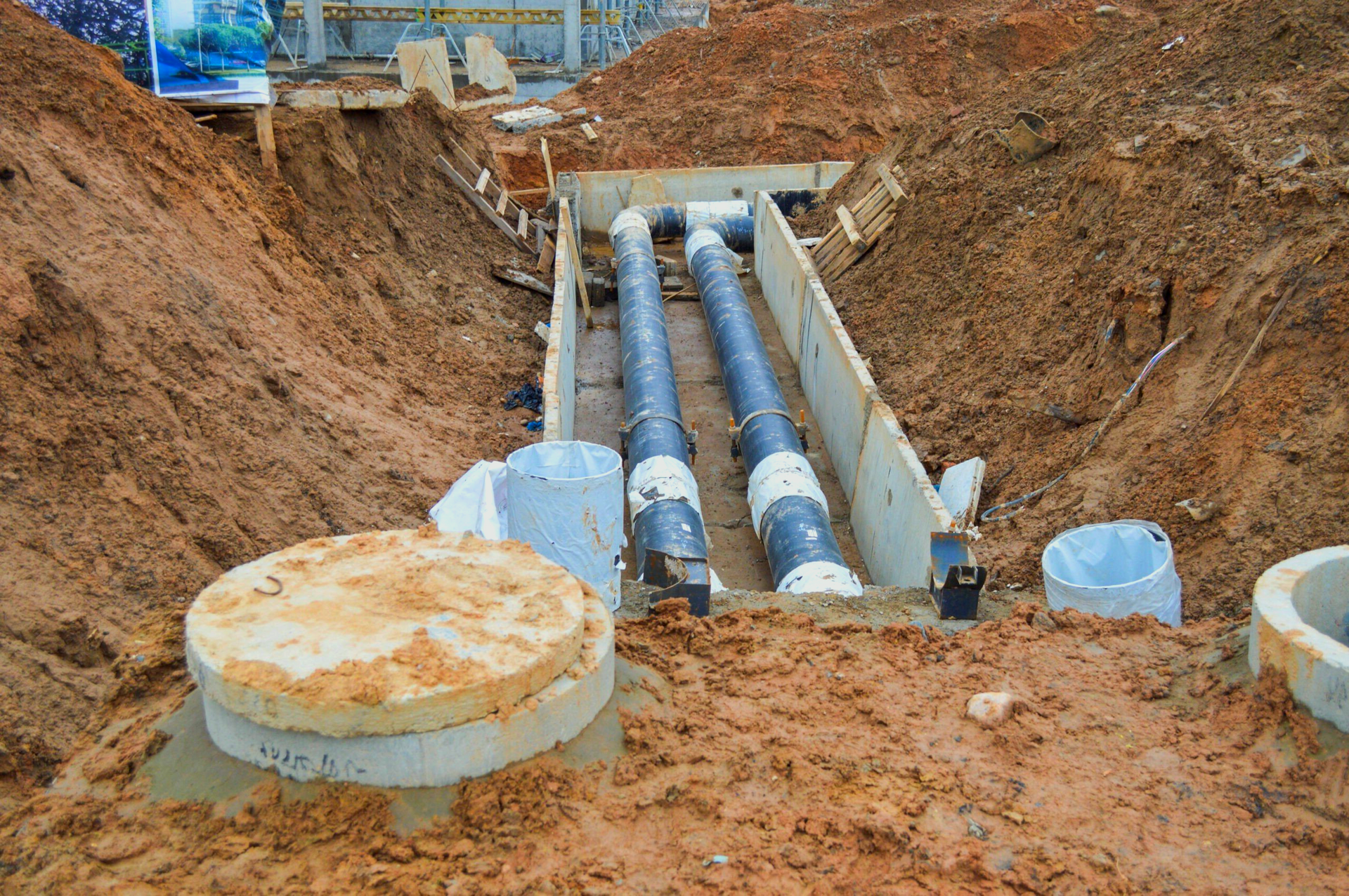 A bunch of pipes are being installed in a trench in the dirt.