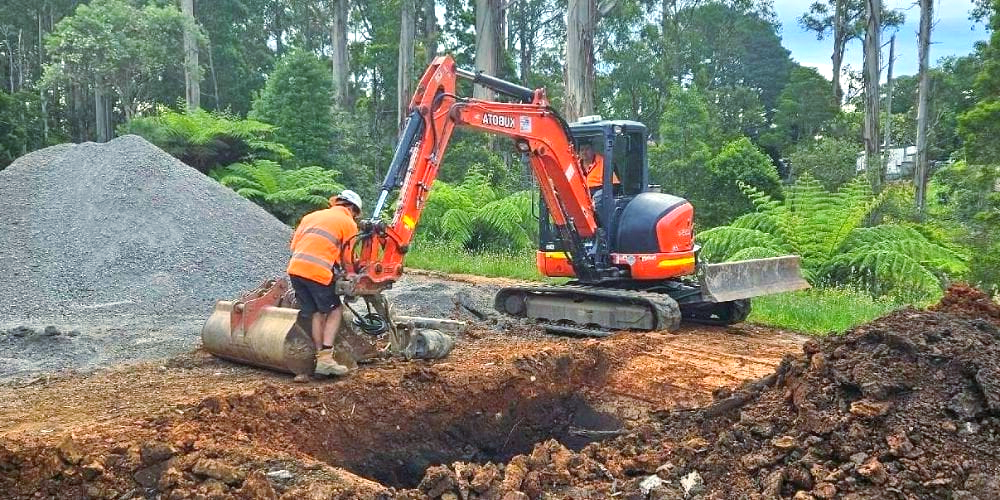 A man is digging a hole in the ground with an excavator.