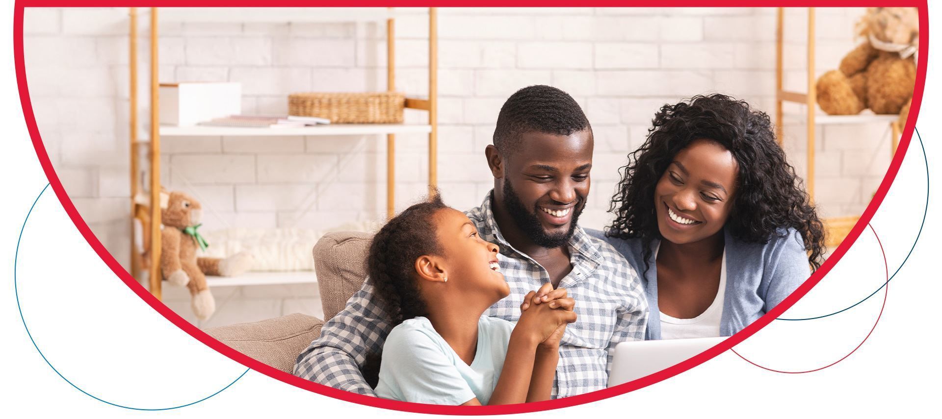A family is sitting on a couch looking at a tablet.