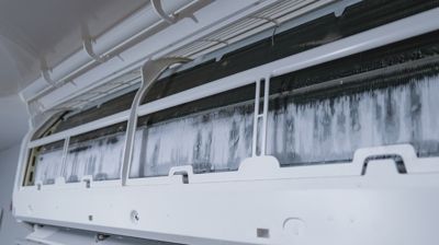 A close up of a white air conditioner with ice on it.